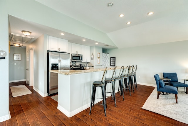 kitchen with white cabinetry, stainless steel appliances, dark hardwood / wood-style flooring, light stone counters, and lofted ceiling