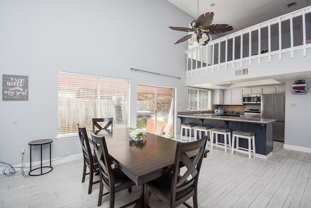 dining room featuring high vaulted ceiling, light wood-type flooring, and ceiling fan