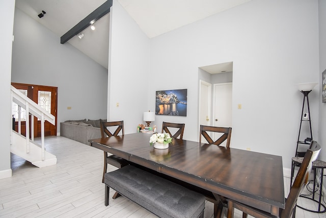 dining space with french doors, beam ceiling, high vaulted ceiling, and light hardwood / wood-style flooring