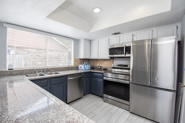 kitchen featuring backsplash, white cabinetry, stainless steel appliances, sink, and blue cabinets