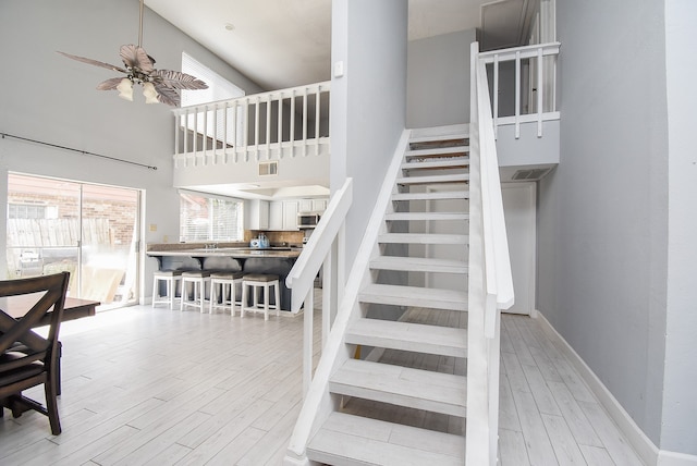 stairway with hardwood / wood-style flooring, a high ceiling, and ceiling fan