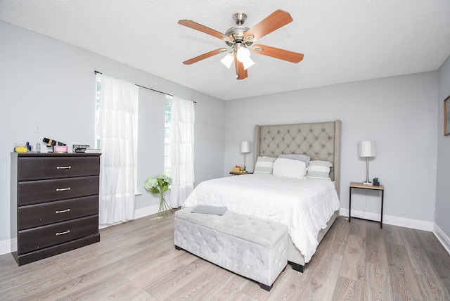 bedroom with light hardwood / wood-style flooring, a textured ceiling, and ceiling fan