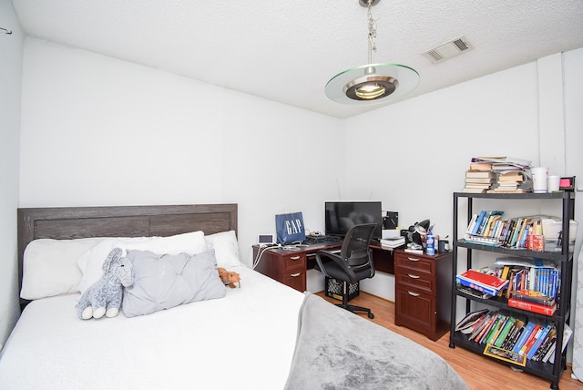 bedroom with a textured ceiling and light wood-type flooring