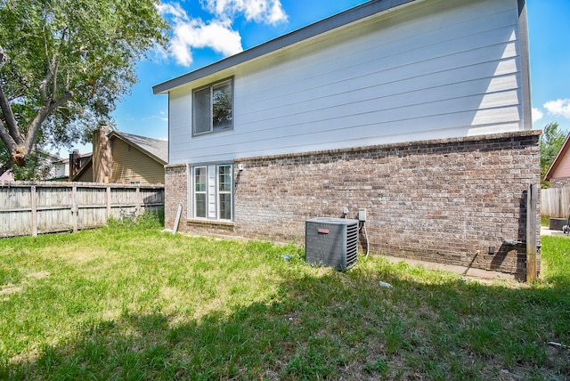 back of property with central air condition unit and a lawn