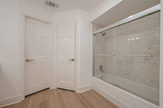 bathroom with hardwood / wood-style flooring and enclosed tub / shower combo