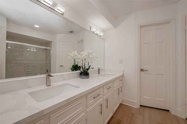 bathroom with wood-type flooring, vanity, and a shower with shower door