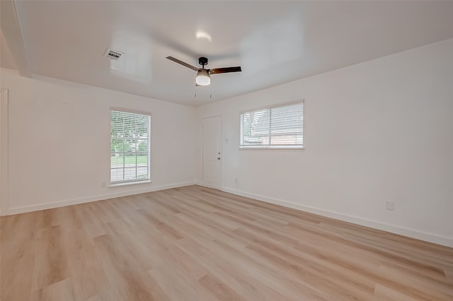 spare room with ceiling fan, light wood-type flooring, and plenty of natural light