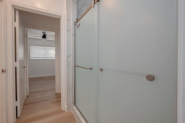 bathroom featuring walk in shower, ceiling fan, and hardwood / wood-style flooring