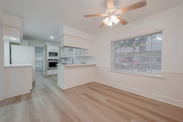 kitchen featuring light wood-type flooring, white cabinetry, kitchen peninsula, appliances with stainless steel finishes, and ceiling fan