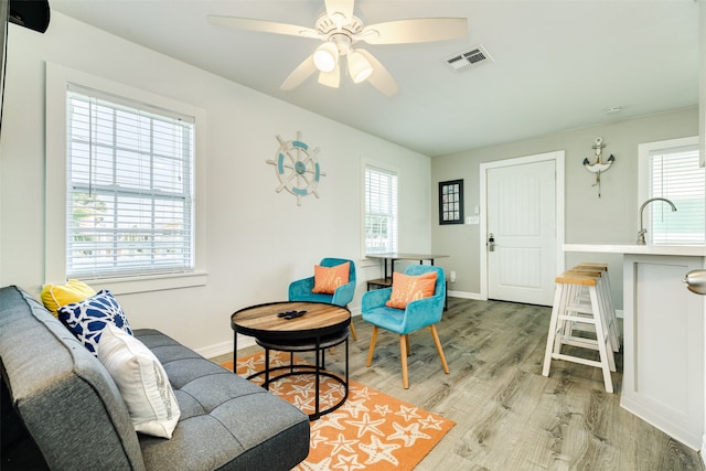 living room with ceiling fan, sink, and light wood-type flooring