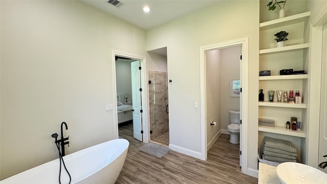 bathroom with built in features, independent shower and bath, toilet, and hardwood / wood-style flooring