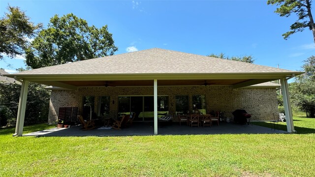 rear view of property featuring ceiling fan, a lawn, and a patio area