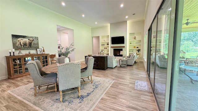 dining space featuring built in shelves, ornamental molding, and light hardwood / wood-style flooring