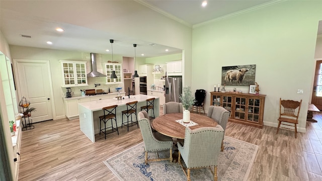 dining area with ornamental molding and light hardwood / wood-style flooring