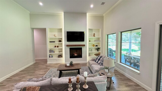 living room featuring ornamental molding, a towering ceiling, and light hardwood / wood-style flooring