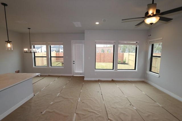 interior space with a healthy amount of sunlight and ceiling fan with notable chandelier