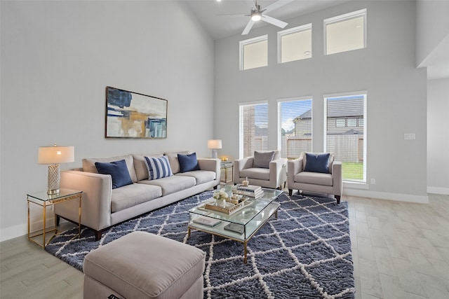 living room with hardwood / wood-style floors, ceiling fan, and high vaulted ceiling