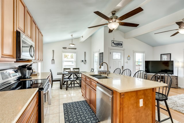 kitchen with a healthy amount of sunlight, stainless steel appliances, sink, ceiling fan, and a kitchen island with sink