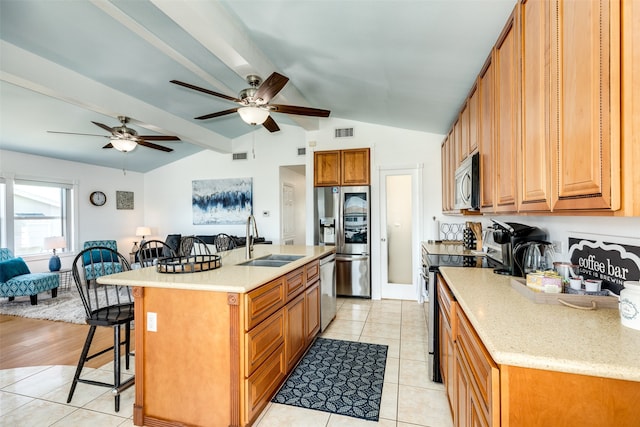 kitchen featuring sink, an island with sink, ceiling fan, appliances with stainless steel finishes, and a breakfast bar