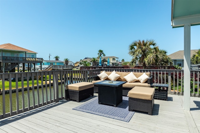 wooden deck with a water view and an outdoor living space with a fire pit