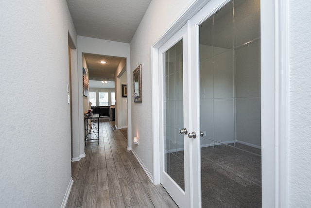 corridor with wood-type flooring and french doors