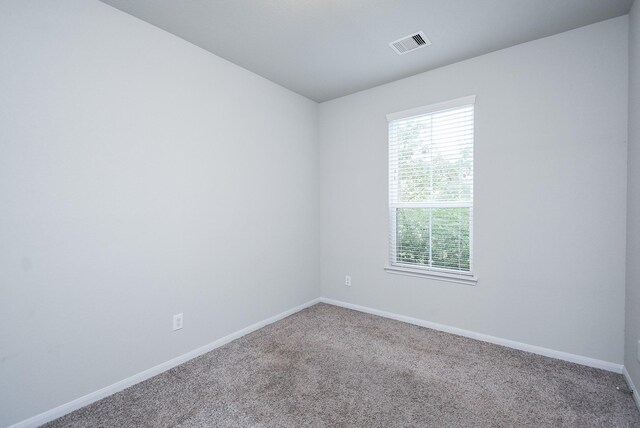spare room featuring carpet, visible vents, and baseboards
