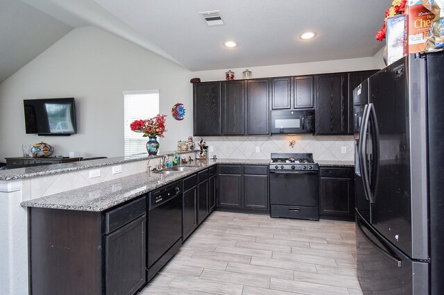 kitchen featuring visible vents, light stone counters, a peninsula, black appliances, and a sink
