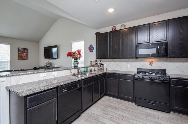 kitchen with a peninsula, lofted ceiling, a sink, black appliances, and tasteful backsplash