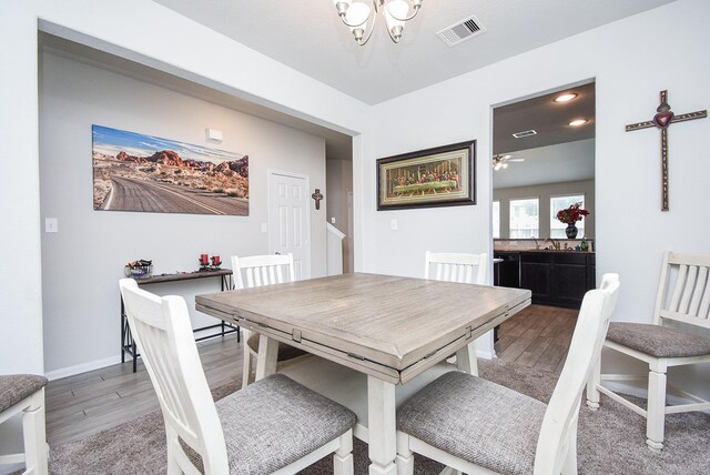 dining space featuring ceiling fan with notable chandelier and hardwood / wood-style floors