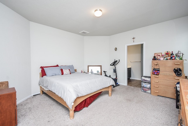 bedroom with connected bathroom and light colored carpet