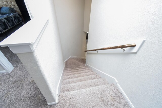 stairs with baseboards, carpet flooring, and a textured wall
