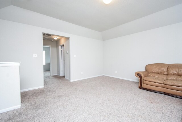 living area featuring visible vents, baseboards, carpet, and vaulted ceiling