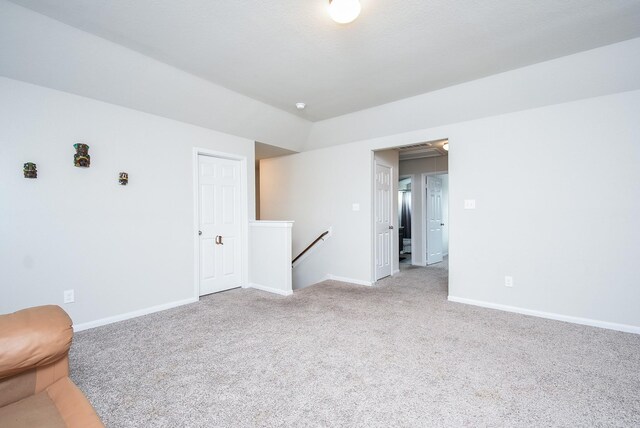 carpeted spare room with baseboards and vaulted ceiling