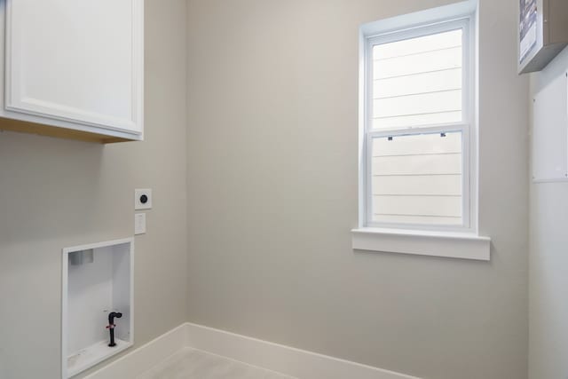 laundry room featuring electric dryer hookup and cabinets