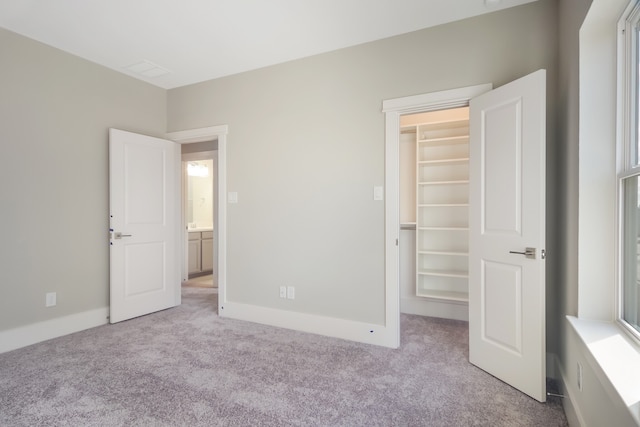 unfurnished bedroom with a walk in closet, light carpet, and a closet