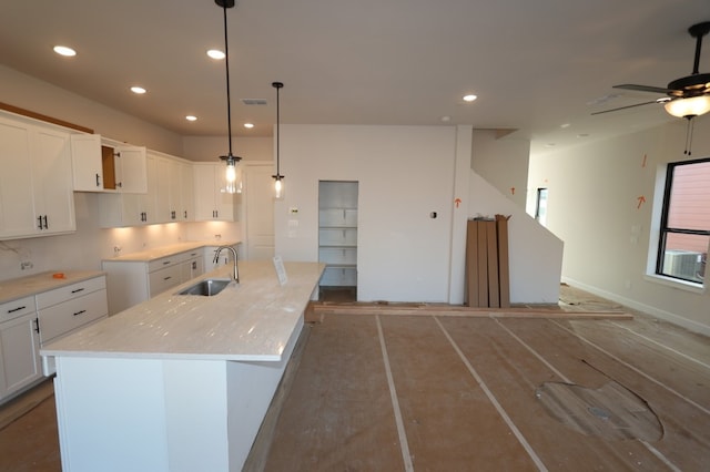 kitchen with ceiling fan, sink, decorative light fixtures, a kitchen island with sink, and white cabinets