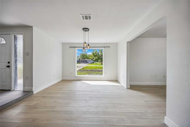 unfurnished dining area with light wood-type flooring and a chandelier