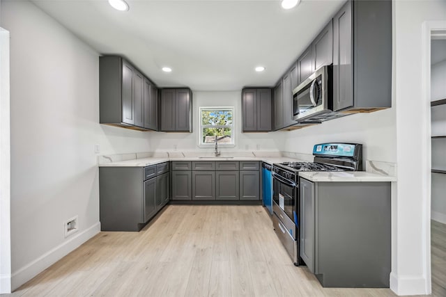 kitchen with gray cabinets, stainless steel appliances, light wood-type flooring, and sink