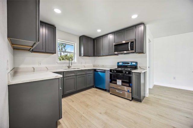 kitchen featuring sink, gray cabinetry, stainless steel appliances, light hardwood / wood-style flooring, and light stone countertops