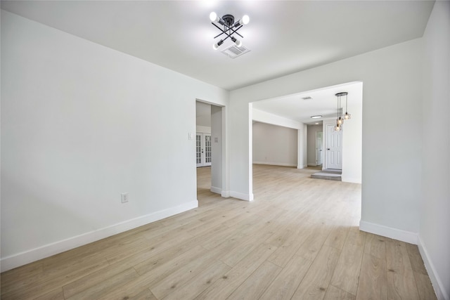 empty room featuring light hardwood / wood-style flooring and an inviting chandelier