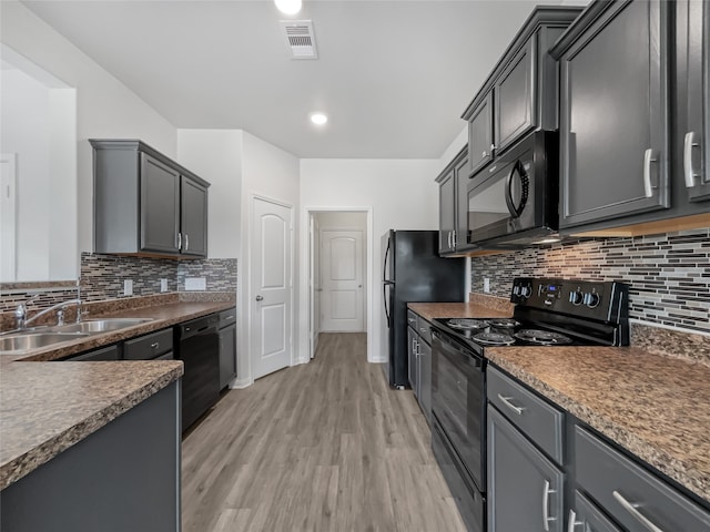 kitchen featuring sink, backsplash, black appliances, gray cabinets, and light wood-type flooring