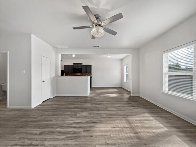 unfurnished living room featuring ceiling fan, dark wood-type flooring, and a healthy amount of sunlight