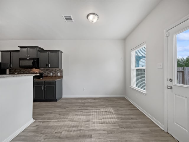 kitchen featuring a healthy amount of sunlight, tasteful backsplash, and hardwood / wood-style flooring