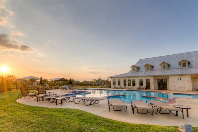 pool at dusk with a lawn and a patio