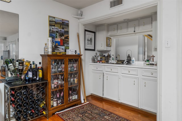 bar featuring sink, white cabinetry, and light hardwood / wood-style floors