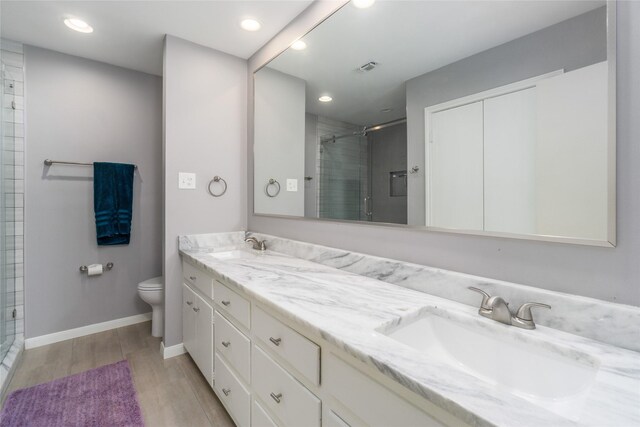 bathroom featuring vanity, toilet, wood-type flooring, and a shower with shower door