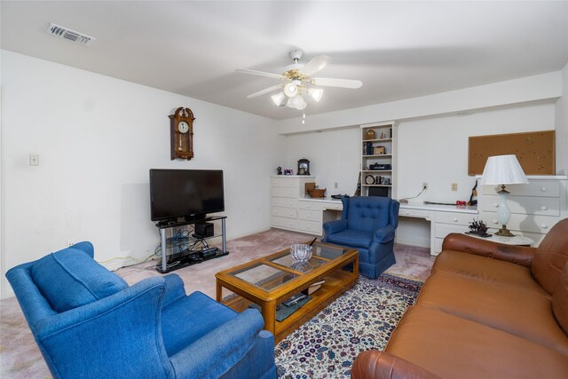 carpeted living room featuring built in desk and ceiling fan