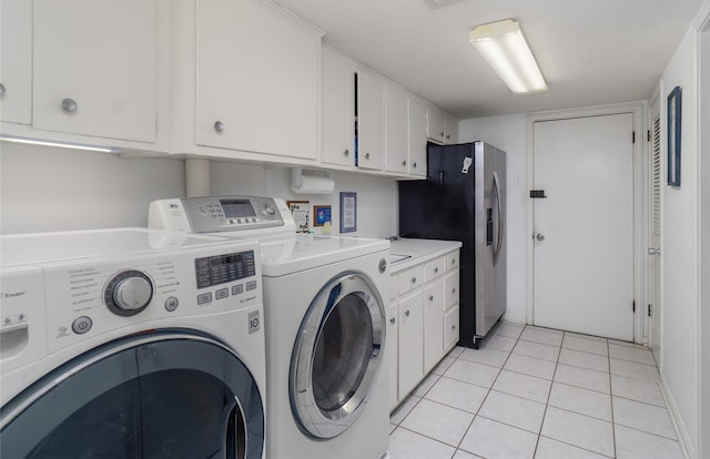 clothes washing area with cabinets, washing machine and dryer, and light tile patterned flooring