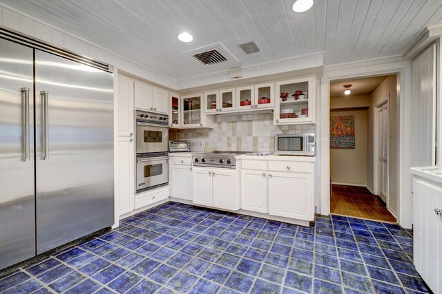 kitchen with decorative backsplash, stainless steel appliances, white cabinets, and wooden ceiling