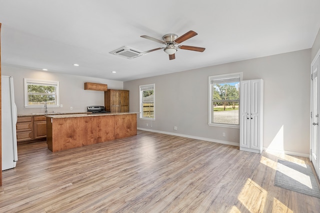 interior space featuring light wood-type flooring, white refrigerator, ceiling fan, and a healthy amount of sunlight